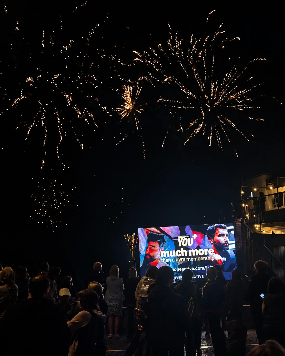 Fireworks above a crowd at night, with our LED screen lit in front of them