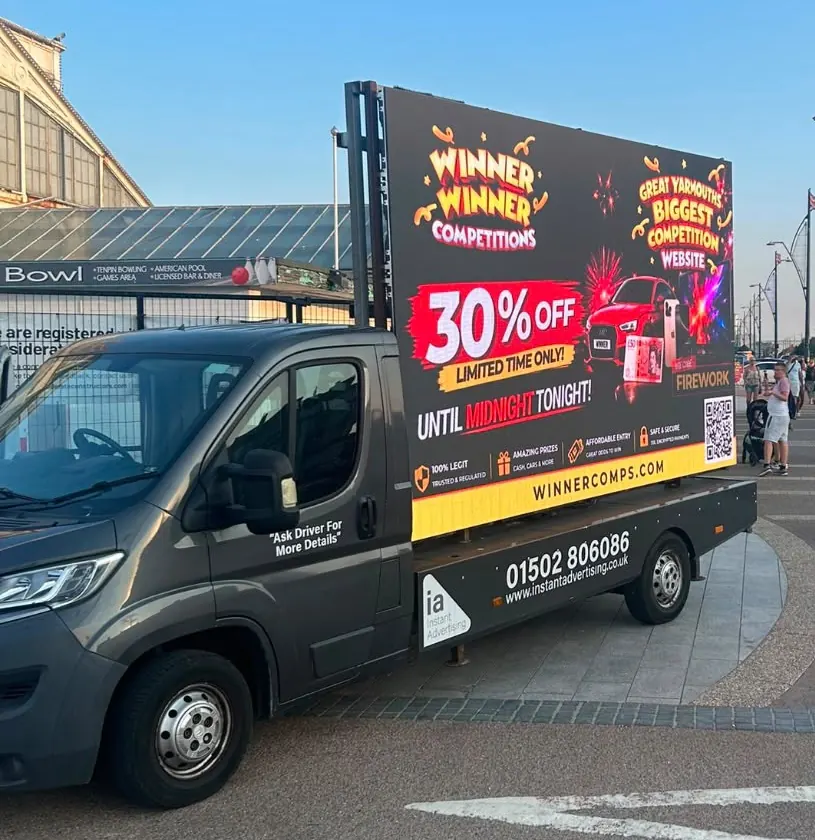 The Instant Advertising digivan parked on the seafront, its screen showing an advert for Winner Winner Competitions